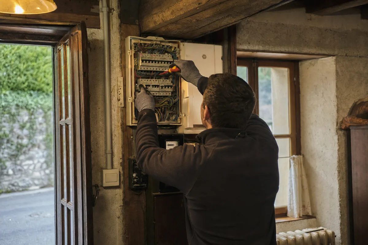 Électricien intervenant sur une installation ancienne dans une maison de village du Genevois